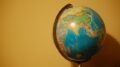 Picture of a colorful globe off center to the right side of the photo against a yellow background.