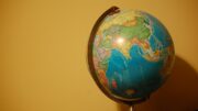 Picture of a colorful globe off center to the right side of the photo against a yellow background.