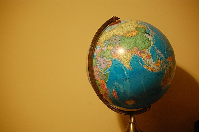 Picture of a colorful globe off center to the right side of the photo against a yellow background.