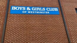 Blue sign reading "Boys & Girls Club of Westminster" on brick wall