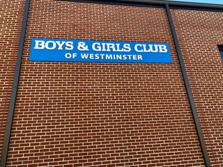 Blue sign reading "Boys & Girls Club of Westminster" on brick wall