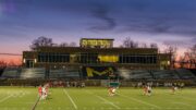 Photo of McDaniel's main sports field during sunset as a game is played.