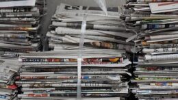 Several stacks of newspapers tied together atop one another.