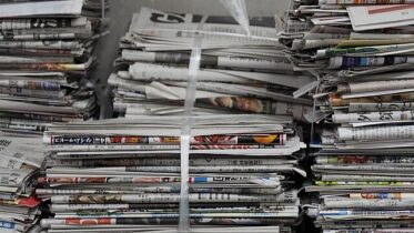 Several stacks of newspapers tied together atop one another.