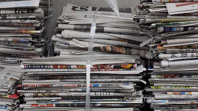 Several stacks of newspapers tied together atop one another.